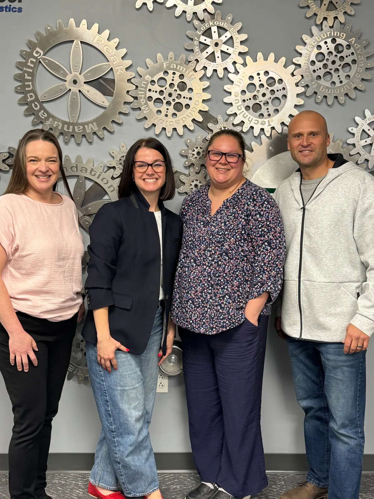 The Able Eyes team standing together in front of a wall of decorative metal gears.